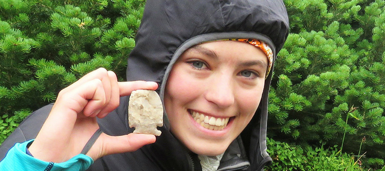A student uncovers an arrowhead on an archaeological dig.