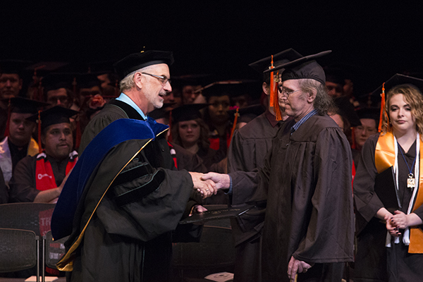 President Tyndall shakes a graduates hand