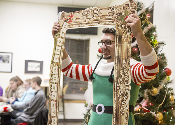 Student dressed as an elf posing while holding a fancy picture frame prop