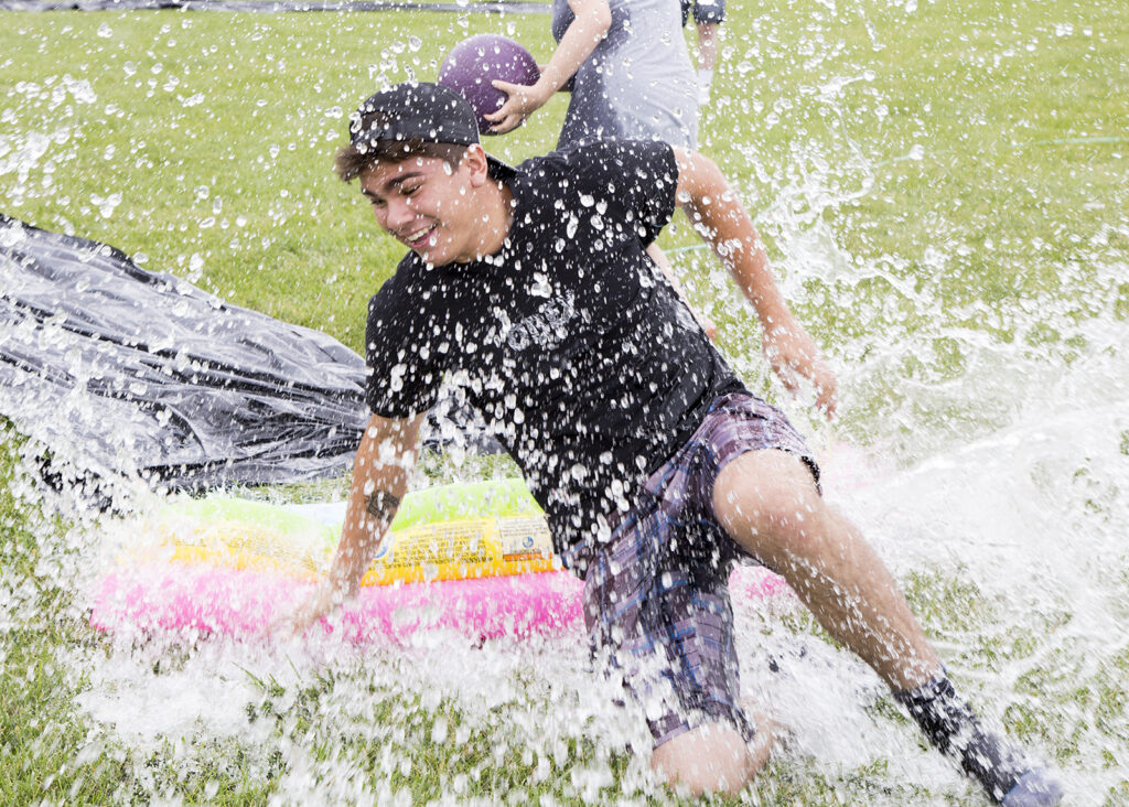 student slides on a slip n' slid and splashes through a small pool