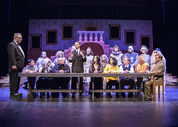 CWC Addams Family cast around a table on stage