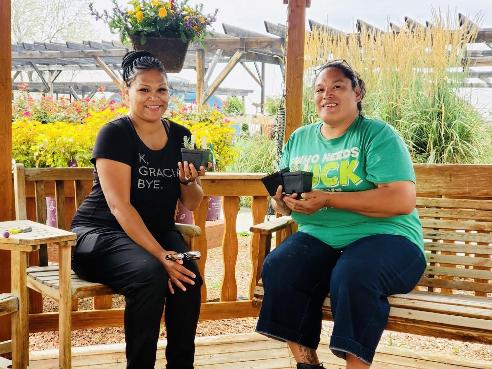 CWC student Deneica Barrett sits with her friend and co-founder Darrah Perez-Good Voice Elk on a bench holding plants