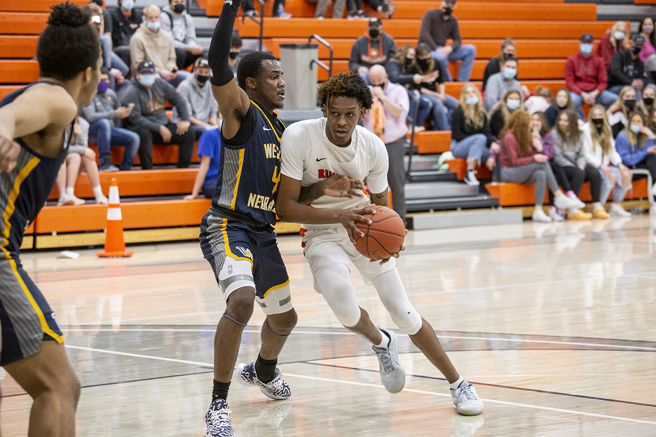 men's basketball dribbles the ball away from the opponent