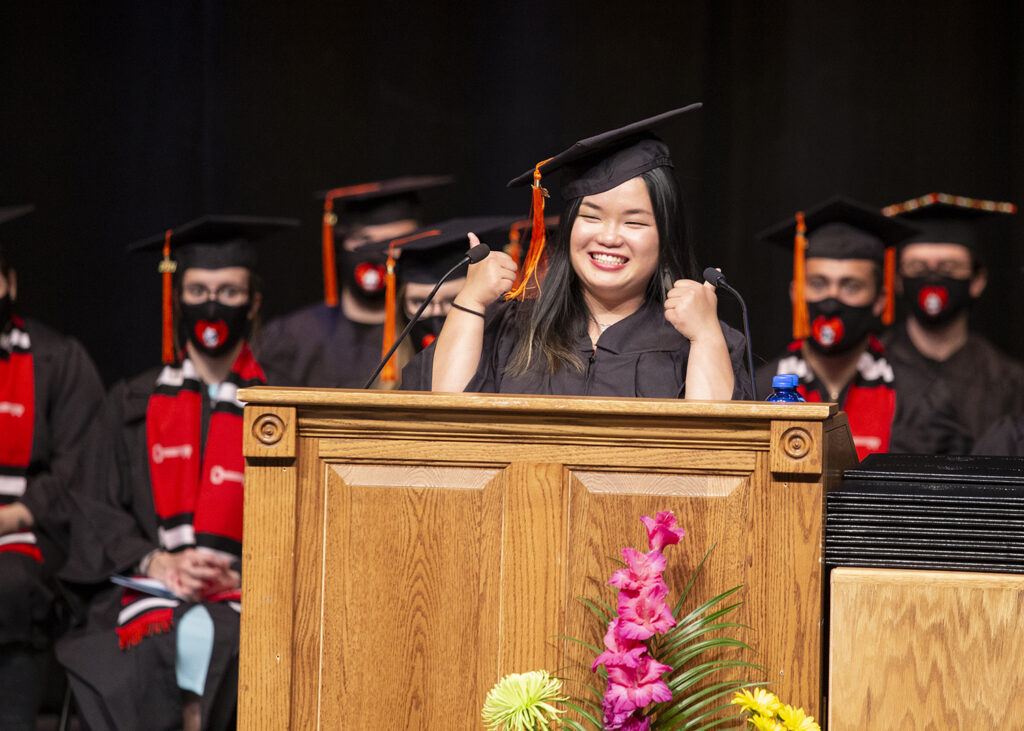 graduate speaker Adele gives two thumbs up on stage