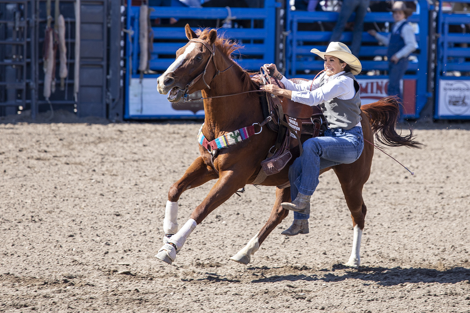 rodeo cowgirl dismounts from her running horse to rope a goat