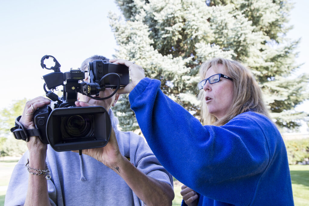 Professor Amanda Nicholoff shows a student how to operate a camera