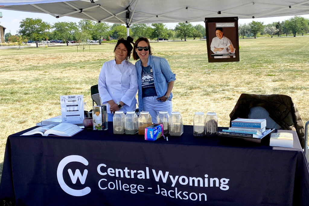 culinary instructor Amy Madera poses with student at an outdoor culinary event