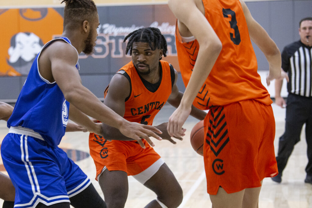 Rustler men's basketball player guards the basketball from the opposite team