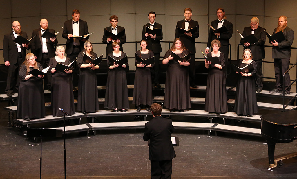 Choral concert singers with our director Jeremy in front conducting