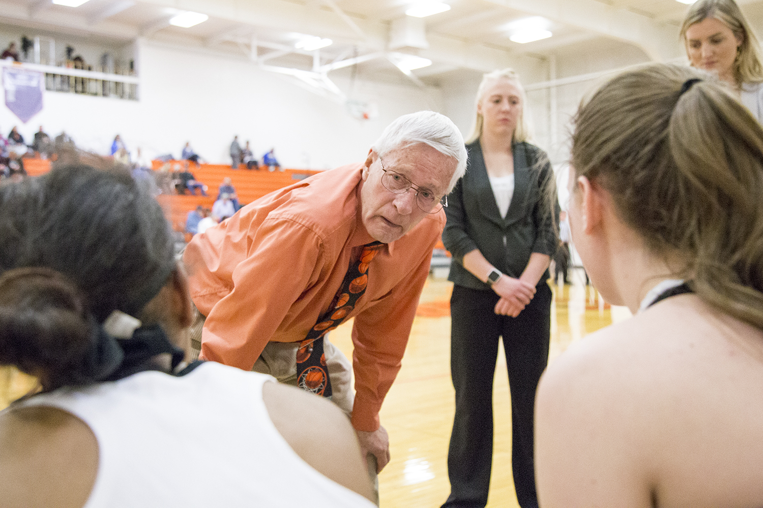 Coach Ken Swartz talks to his women's basketball team on the sidelines of a basketball game