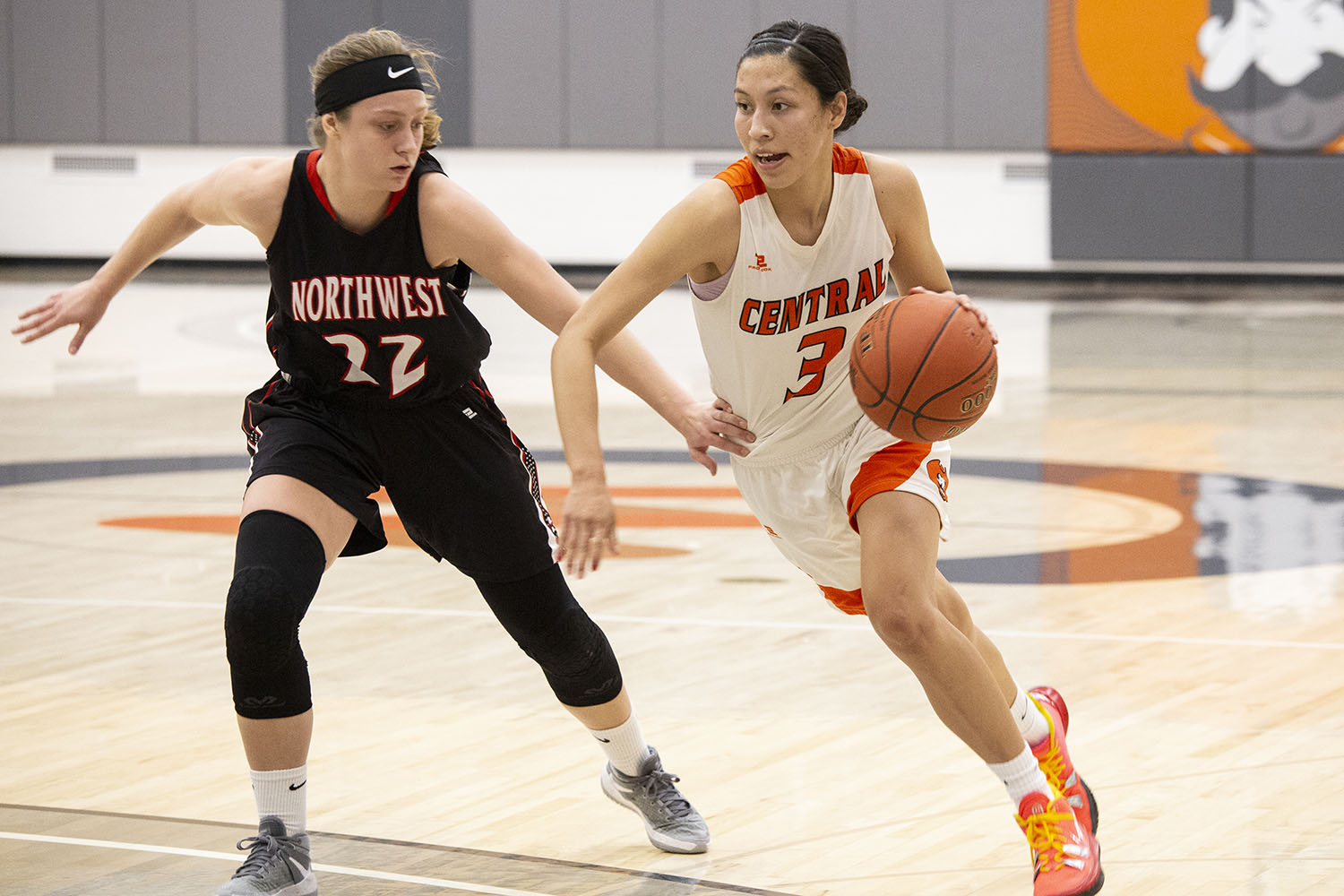 CWC women's basketball player darts with the ball around opposing player