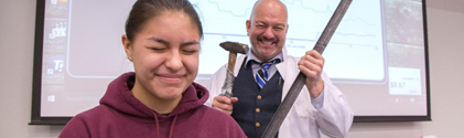 Student being demonstrated the effects of a piece of metal being hammered